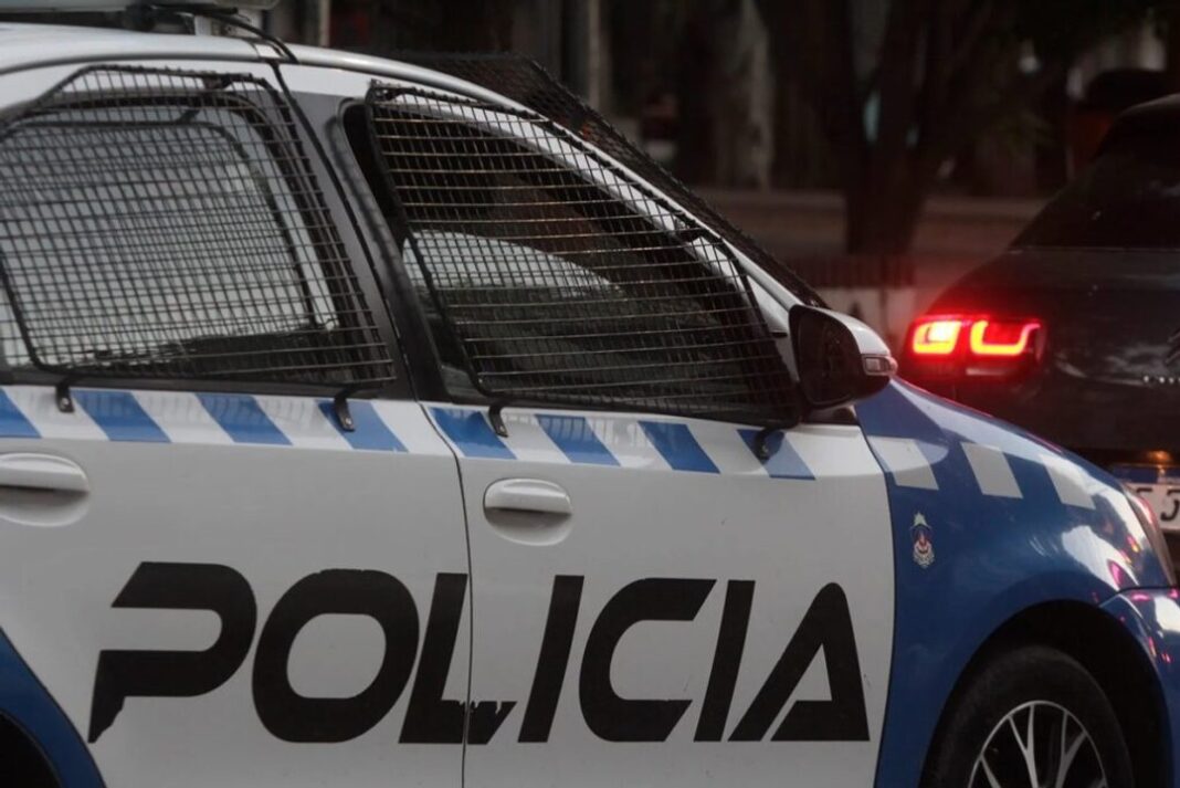 Ilustración de ambulancia y cinta policial en una calle urbana, representando un hecho violento.