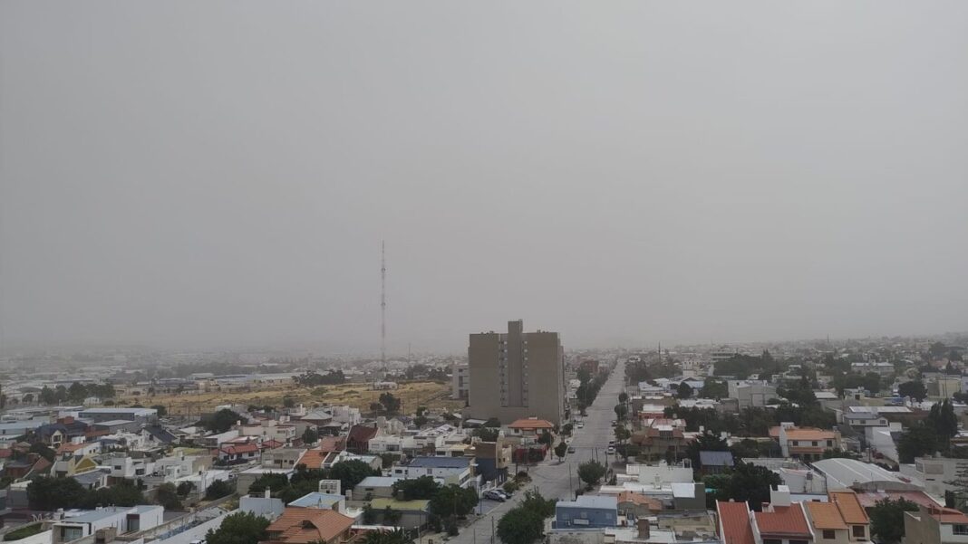 Vista de la costa de Comodoro Rivadavia con cielo nublado y banderas ondeando por el viento