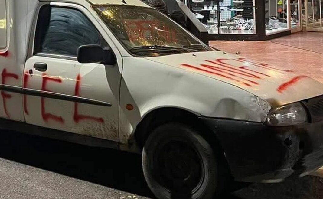 Vehículo utilitario blanco vandalizado con la palabra Infiel pintada en rojo en el capó y laterales.