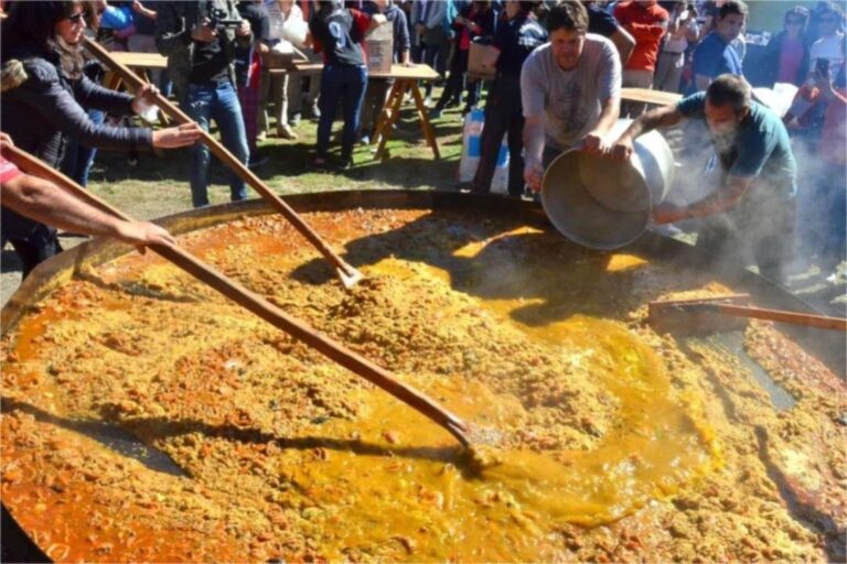 Preparación de la paella gigante en una paellera de tres metros de diámetro en Villa Pehuenia, con cocineros trabajando.