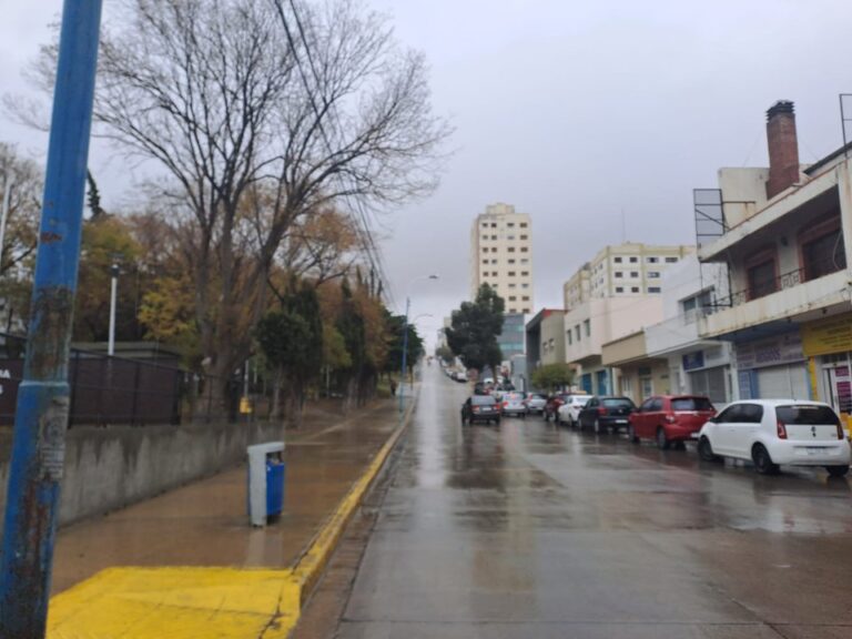 Lluvia en calles de Comodoro Rivadavia con cielo nublado y mar agitado de fondo