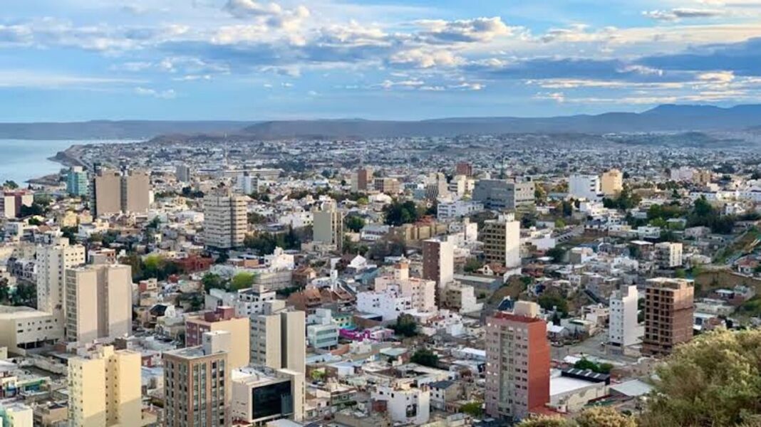 Calle de Comodoro Rivadavia con cielo nublado y árboles movidos por el viento