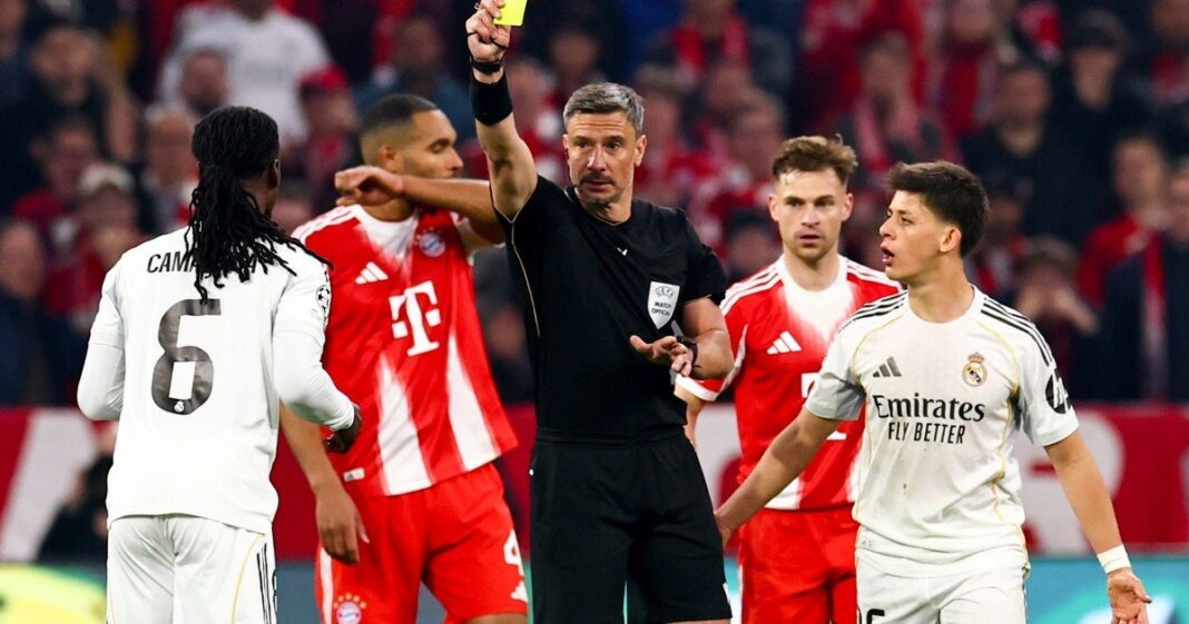 Árbitro de fútbol mostrando tarjeta amarilla en un partido de la Champions League